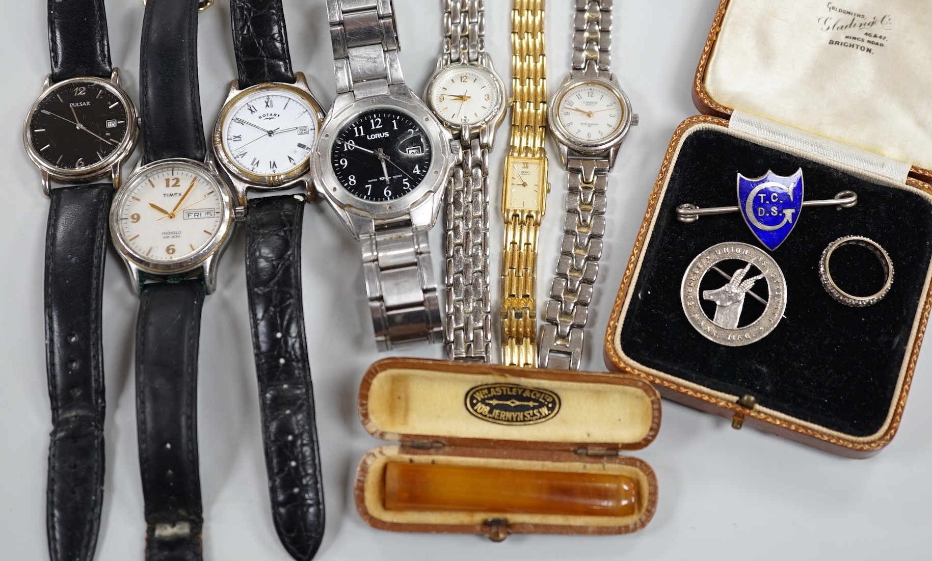 Seven assorted modern wrist watches including Pulsar and Rotary, a 9ct and 'silver' eternity ring, a case amber cigarette holder and two white metal brooches, including one with enamel.